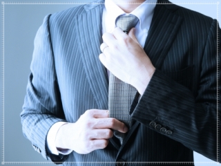 スーツ姿でネクタイを締める男性画像